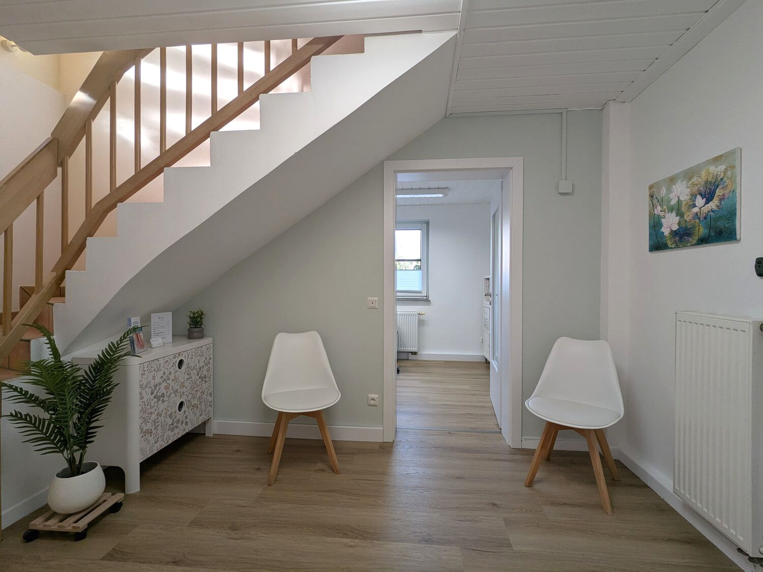 Einladender, heller Wartebereich der Praxis mit Sitzgelegenheiten, Treppe und Pflanzen